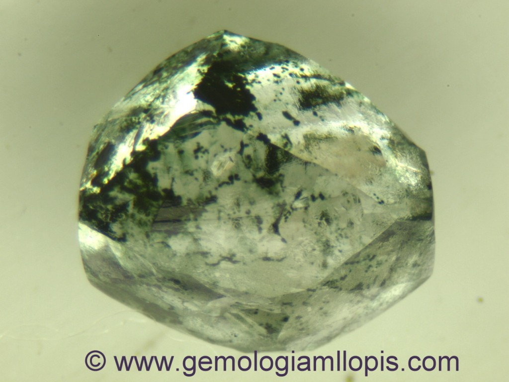 Bruto de diamante tratado por irradiación. Observar las manchas oscuras que vistas con lupa son verdosas